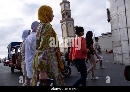 Femme vêtue d'un voile musulman sur la place des Nations Unies avec la tour de l'horloge à l'entrée de la médina en arrière-plan à Casablanca à Moroc Banque D'Images