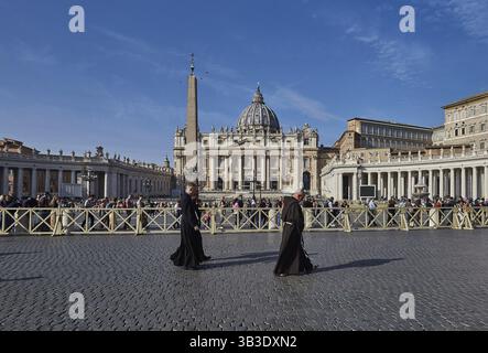 Les moines traversent la place Saint-Pierre à Rome, caractérisée par l'imposante façade de la basilique Saint-Pierre et un obélisque Rome Italie Banque D'Images