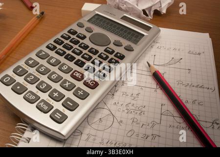 Ordinateur portable avec table en désordre, crayons, papiers froissés et calculatrice Banque D'Images