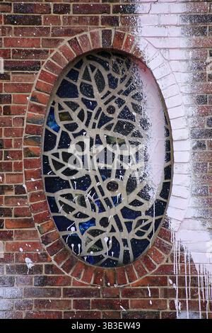 Mosaïque de vitraux avec des motifs géométriques dans un mur de briques altérées avec des éclaboussures de peinture. Banque D'Images