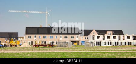 Un site de construction dynamique présente de nouveaux bâtiments résidentiels avec des grues et de la machinerie lourde dans une zone en développement. La lumière du soleil met en évidence la progression animée du projet. Banque D'Images
