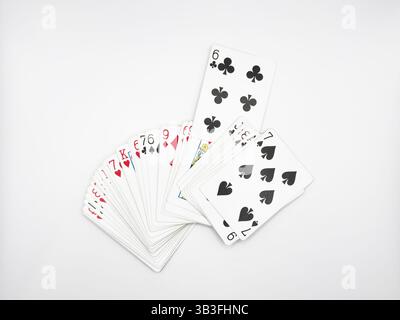 Les cartes de poker en plastique blanc se sont étendues au centre de l'image avec un six de trèfles allongés sur un fond blanc Banque D'Images
