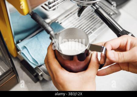 Préparation de mousse de lait à l'aide d'une machine à cappuccino professionnelle pour boissons au café Banque D'Images