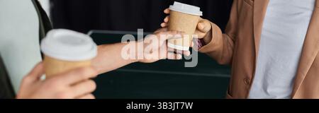 Deux professionnels s'engagent dans la conversation tout en partageant des tasses à café dans un cadre de bureau animé. Banque D'Images