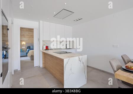 Cuisine élégante avec îlot de marbre, plaque de cuisson intégrée et vue sur une chambre confortable. Banque D'Images