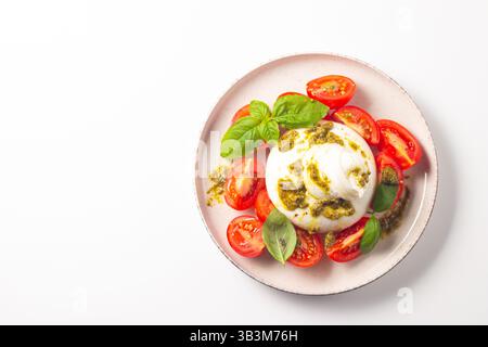 Salade caprese au fromage Burrata avec tomates cerises, huile d'olive, pesto et assaisonnement. Concept de nourriture fraîche. Banque D'Images