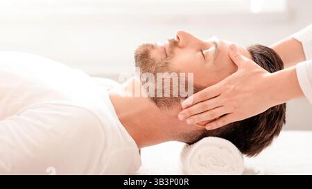 Femme thérapeute faisant un massage relaxant de la tête pour l'homme beau Banque D'Images