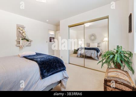 Une chambre magnifiquement conçue avec un lit, un coffre pour le rangement et d'élégantes portes vitrées coulissantes qui s'ouvrent à l'air frais et à la lumière Banque D'Images