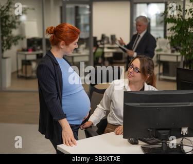 Deux femmes caucasiennes parlant pendant les heures de travail. Le patron est malheureux. Banque D'Images