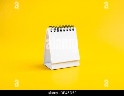Espace blanc de la page blanche du calendrier en spirale de bureau pour le concept d'organisateur pour planifier et rappeler, isolé sur fond jaune. Maquette petite table calen Banque D'Images