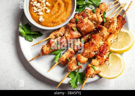 Brochettes satay de poulet grillé avec sauce aux cacahuètes épicée. Sate ayam. Repas thaïlandais asiatique. Banque D'Images