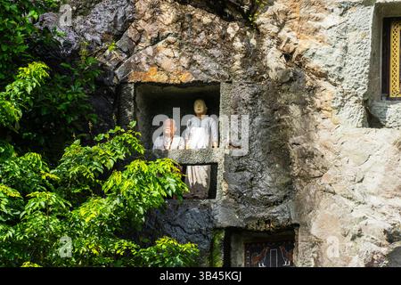 De spectaculaires effigies en bois grandeur nature ou tau tau des défunts sont nichées parmi les cryptes. Le site funéraire de Lemo est l'un des plus anciens sites de Toraja. Banque D'Images