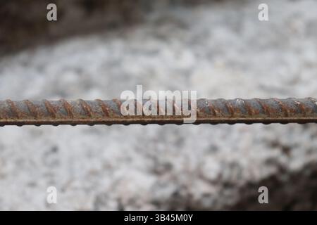 Le cliché détaillé à hauteur des yeux présente les textures des barres d'armature en acier corrodé, l'alignement horizontal avec un peu de rouille, offrant une sensation industrielle et brute. Banque D'Images