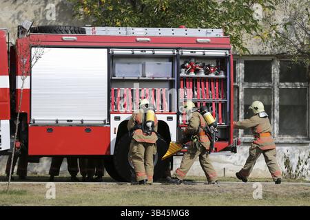 Les pompiers participent à une formation où ils éteignent le feu d'une voiture écrasée sur un autre véhicule. Camion de pompiers rouge, moteur de pompiers Banque D'Images
