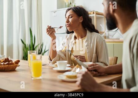 Un couple aimant profite d'un délicieux repas ensemble dans leur maison confortable, savourant chaque moment. Banque D'Images