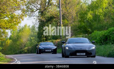Whittlebury,Northants.,.UK - 27 avril 2025 : deux voitures Aston Martin Vantage conduisant sur une route de campagne anglaise. Banque D'Images