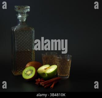 Kiwi et liqueur de pomme verte avec cannelle et anis dans une carafe en cristal sur fond noir. Gros plan. Banque D'Images