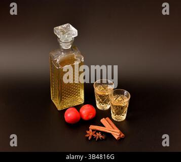 Liqueur de prune à l'anis et à la cannelle, alcool maison fort dans une carafe et deux verres en cristal sur fond noir. Gros plan. Banque D'Images