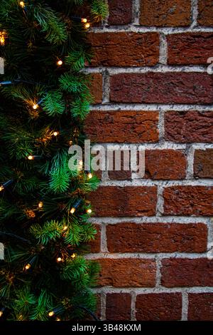 Gros plan vertical d'un mur de briques avec guirlandes. Fond de Noël Banque D'Images
