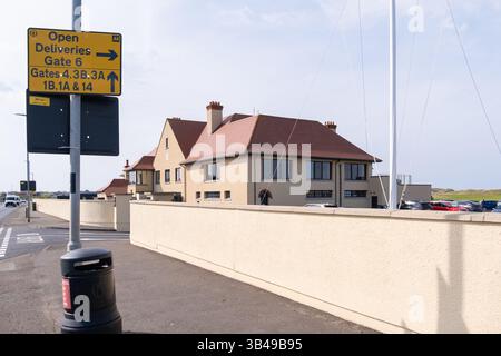 Portrush, Irlande du Nord - 29 avril 2025 : entrée au Royal Portrush Golf Club avec vue sur le clubhouse et les panneaux de préparation à l'Open Championship Banque D'Images