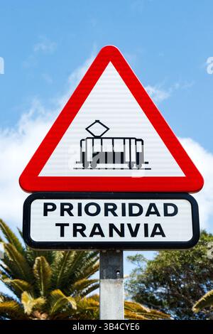 Gros plan d'un panneau d'avertissement de tramway prioritaire espagnol contre un ciel bleu clair et des palmiers - tenerife canaries - prioridad tranvia Banque D'Images