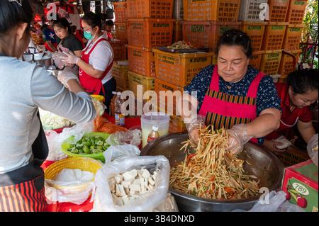 Un vendeur de fruits préparant un grand bol de salade mixte pour ses clients réguliers et la cérémonie de remise de l'aumône bouddhiste à l'un des étals de fruits avec une wid Banque D'Images