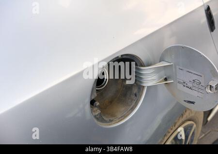 Voiture argentée garée à l'extérieur avec le bouchon de carburant ouvert, révélant le réservoir de carburant et les détails du bouchon à la lumière du jour. Banque D'Images