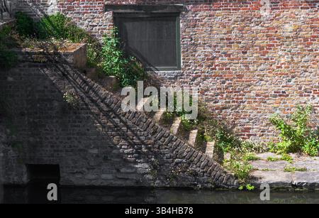 Un mur de briques pleines avec une fenêtre installée dedans, ainsi qu'un escalier qui mène à cette fenêtre, fournissant l'accès Banque D'Images