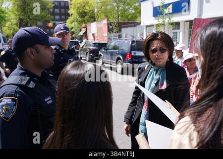 Une femme en manteau noir parle avec deux officiers du NYPD. Deux femmes aux cheveux longs se tiennent derrière elles. Les voitures et une rue sont visibles en arrière-plan. Banque D'Images