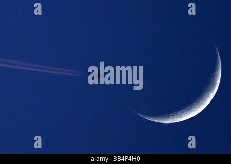 Mnichovo Hradiste, République tchèque. 30 avril 2025. Un Embraer 170 exploité par LOT Polish Airlines, en route de Bergame à Gdansk, survole le croissant de lune au-dessus de la République tchèque. (Crédit image : © Slavek Ruta/ZUMA Press Wire) USAGE ÉDITORIAL SEULEMENT ! Non destiné à UN USAGE commercial ! Banque D'Images