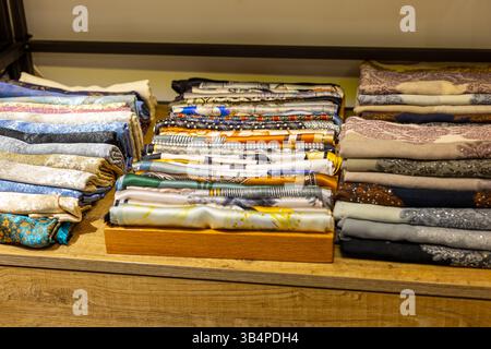 Des tissus soigneusement disposés de différentes couleurs et motifs remplissent les étagères d'un magasin de textile. Les clients parcourent la collection, inspirée par le plongeur Banque D'Images