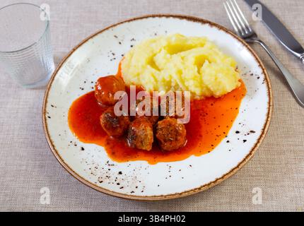 assiette ronde blanche avec boulettes de viande saupoudrées d'aneth haché dans une sauce tomate avec purée de pommes de terre Banque D'Images