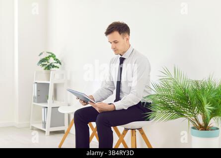 Jeune homme d'affaires assis sur la chaise avec des documents préparant pour la réunion ou la conférence. Banque D'Images
