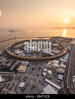 Vue aérienne d'Osaka Expo 2025 Japon, vue en hélicoptère du coucher du soleil du Grand Ring et des pavillons de campagne sur l'île de Yumeshimanaka Banque D'Images