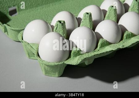 Carton vert boîte à oeufs sur fond gris, beaucoup d'oeufs sont dans la boîte. Banque D'Images
