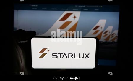 2 avril 2025, Allemagne : dans cette illustration photo, une personne tient un téléphone portable avec le logo de la compagnie aérienne taïwanaise Starlux Airlines sur l'écran devant la page Web. (Crédit image : © timon Schneider/SOPA images via ZUMA Press Wire) USAGE ÉDITORIAL SEULEMENT ! Non destiné à UN USAGE commercial ! Banque D'Images