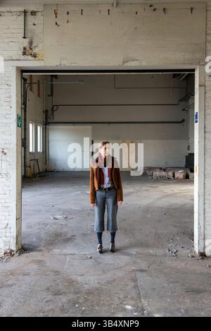 Portrait femme biaisée de genre, portant la mode masculine dans un environnement industriel. Tilburg, pays-Bas. MR=OUI Banque D'Images