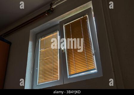 Fenêtre inclinée ouverte avec stores fermés dans une pièce Banque D'Images