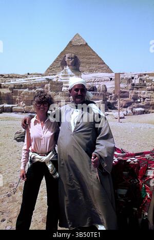 Égypte. Gizeh. Femme touriste posant avec un homme local devant le Grand Sphinx. Banque D'Images