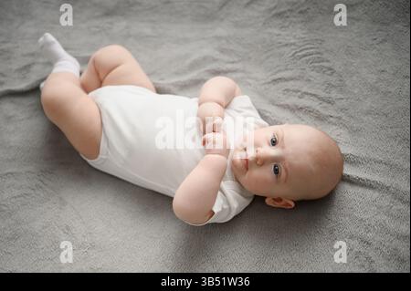 Le nouveau-né est allongé dans un berceau, bouge ses bras et ses jambes et regarde sa mère. Bébé est le monde de l'apprentissage, attendant sa mère, calme, attendant de nourrir, g Banque D'Images