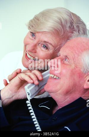 Gros plan d'un homme et d'une femme seniors en pyjama parlant au téléphone. Banque D'Images