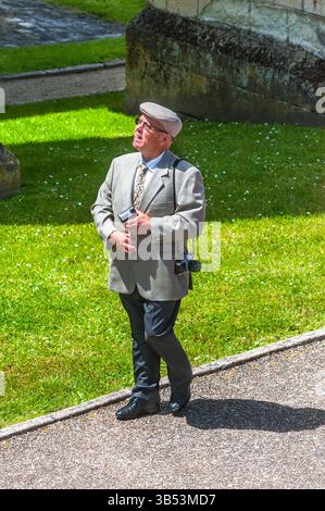 Homme avec une caméra au-dessus de son épaule regardant vers le soleil brillant - Preuilly-sur-Claise, Indre-et-Loire (37), France. Banque D'Images