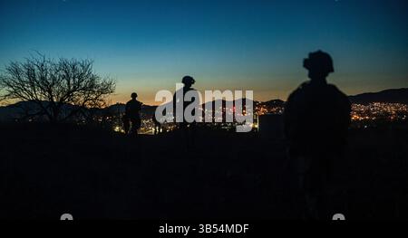 Soldats américains de la compagnie Bravo, 2e bataillon, 12e régiment d'infanterie, 2e équipe de combat de la brigade Stryker, 4e division d'infanterie, affectés à la Force opérationnelle interarmées - patrouille frontalière sud le long de la frontière sud alors que le soleil se couche près de Nogales, Ariz., 23 mars 2025. Le 20 mars 2025, le secrétaire à la Défense a autorisé un soutien renforcé de détection et de surveillance au Service des douanes et de la protection des frontières des États-Unis (CBP), permettant aux militaires de patrouiller à pied ou à l'aide de véhicules tactiques militaires pour signaler au CBP des activités illégales soupçonnées. Sous la direction du US Northern Command, la JTF-SB s'aligne Banque D'Images