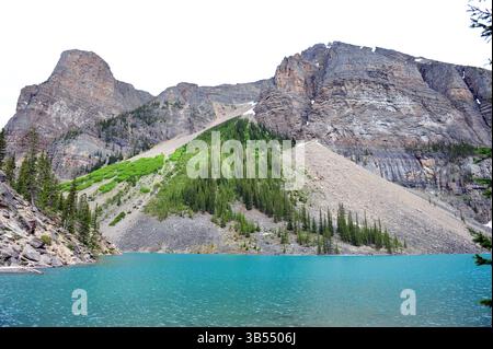 Montagnes rocheuses et lac turquoise dans le parc national Banff, Alberta, Canada, avec forêt alpine et pentes abruptes sous la lumière du jour. Banque D'Images