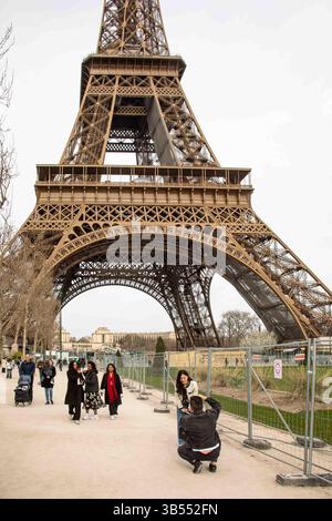 Touristes prenant des photos sur le champ de mars avec la Tour Eiffel en arrière-plan à Paris, France Banque D'Images