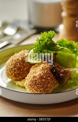 De délicieuses côtelettes de poulet panées sont servies dans une assiette avec de la purée de pommes de terre et de la salade fraîche, créant un repas appétissant Banque D'Images