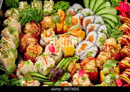 Assiette de sushis vibrante avec un assortiment de maki, uramaki et nigiri, garnie de légumes frais et de fleurs comestibles Banque D'Images