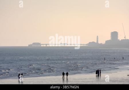 Les gens marchant sur la plage de Shoreham West Sussex avec Worthing Pier au loin Banque D'Images