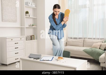 Jeune femme avec pantoufle regardant dans le dégoût des cafards sur la table blanche à l'intérieur. Problème de ravageur Banque D'Images