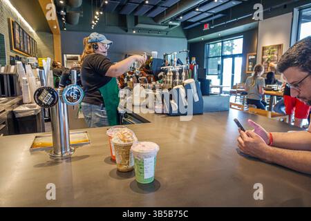 Davenport Florida, café Starbucks, comptoir intérieur, travailleur de barista femme, casque et tablier vert, homme de client utilisant smartphone, int de café Banque D'Images